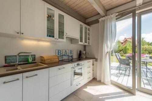 a kitchen with white cabinets and a view of a patio at Villa Mela in Mikołajki