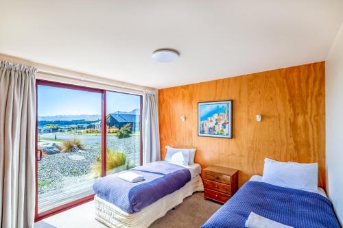 a bedroom with two beds and a large window at Castle Hall - Lake Tekapo in Lake Tekapo