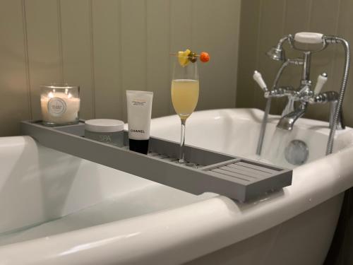 a bathtub with a tray with a wine glass and candles at Little Broad Cottage Norfolk 2 Bedroom Sleep 4 in Great Yarmouth
