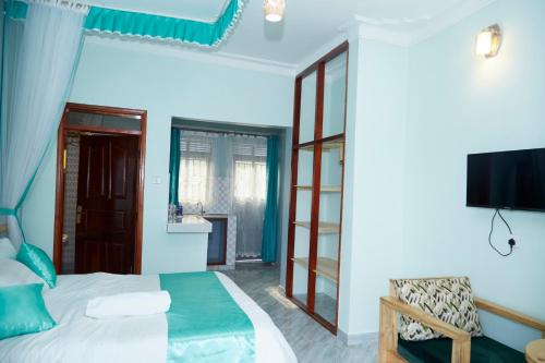 1 dormitorio con 1 cama y TV en la pared en WestWay Luxury Suites, en Mbarara