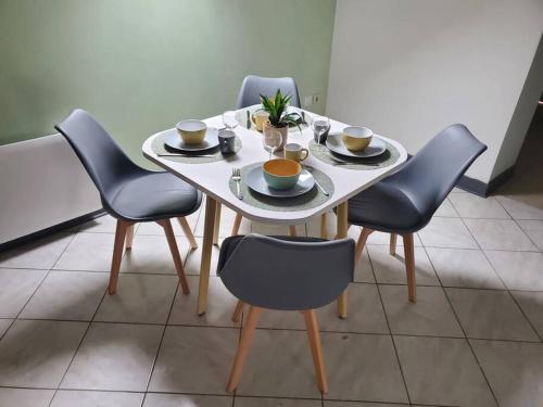 a table with four chairs and a white table with cups and plates at Studio Ferme de la manufacture in Essigny-le-Grand
