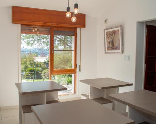 una cocina con 2 mesas y una ventana grande en Casa en centro de Carlos Paz con pileta en Villa Carlos Paz