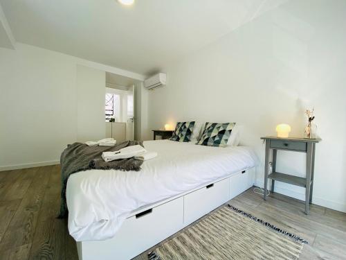 a bedroom with a large white bed with a desk at Tia Anica House I - apartment with terrace in central Fuseta beach village in Fuzeta