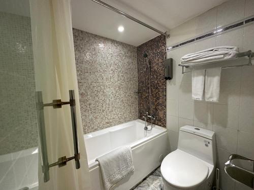 a bathroom with a tub and a toilet and a sink at Link World Hotel in Taipei