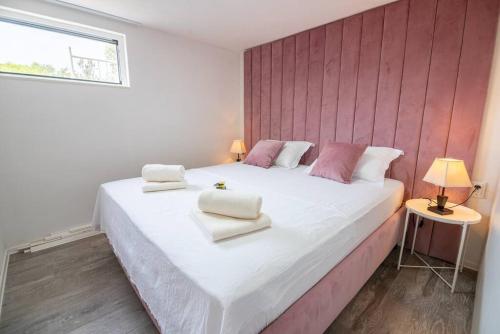 een slaapkamer met een groot wit bed met roze muren bij Perina Haven - Island Vis Beachfront in Rogačić