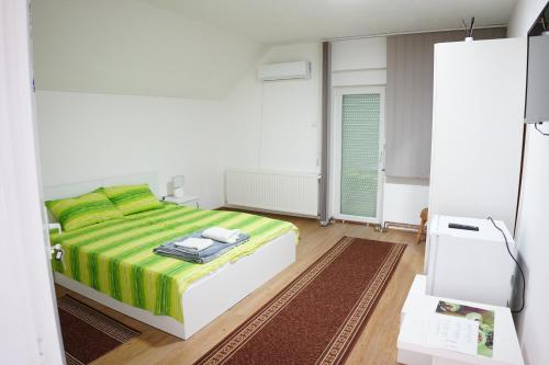 a bedroom with a bed with a green and yellow blanket at Rooms Busujok in Kladovo
