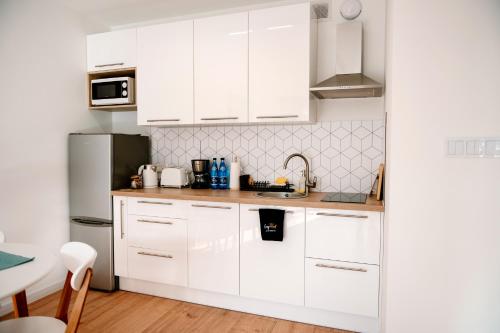 a white kitchen with white cabinets and a refrigerator at Golden Port SPA - Easy-Rent Apartments in Dziwnów
