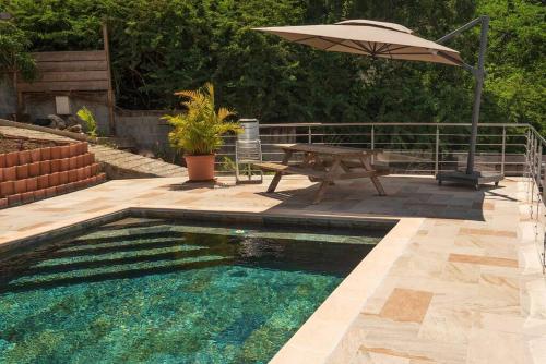 a swimming pool with a picnic table and an umbrella at BAS DE VILLA PISCINE PETIT VERSAILLES SAINTE ANNE in Sainte-Anne