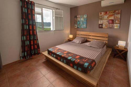 a bedroom with a wooden bed in a room at BAS DE VILLA PISCINE PETIT VERSAILLES SAINTE ANNE in Sainte-Anne