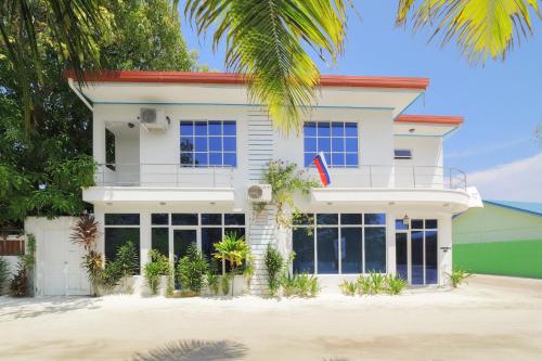 a house on the beach with a palm tree at Sevinex Inn in Feridhoo