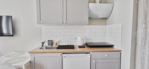 kuchnia z białymi szafkami i zlewem w obiekcie Apartamenty Świętojańska Gdynia Centrum w mieście Gdynia