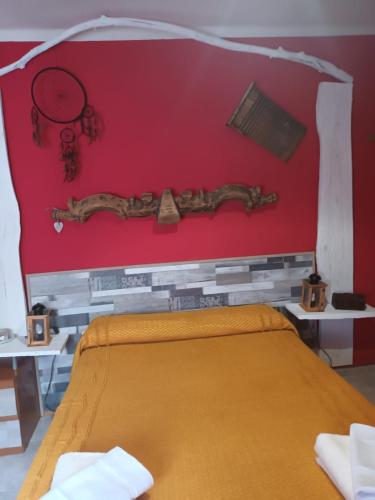 a bedroom with a bed and a red wall at Balcón de los enanos in Béjar