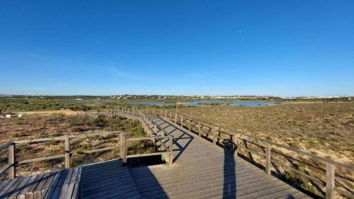 a wooden boardwalk over a beach with a lake at Cantinho do Mocho in Pêra