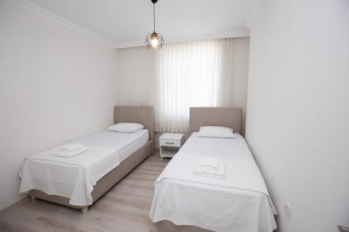 two beds in a room with white walls and wooden floors at Villa Cennet Dalaman 11 in Dalaman