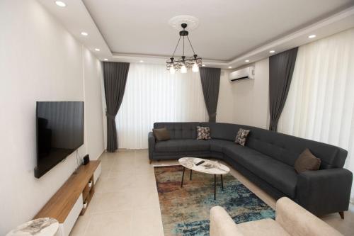 Una sala de estar con un sofá negro y un televisor. en Villa Cennet Dalaman 11, en Dalaman