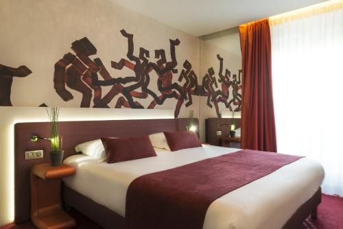 1 dormitorio con 1 cama con una pintura en la pared en Le Bon Hôtel, en Neuilly-sur-Seine
