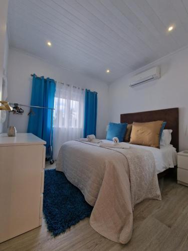 Quinta do Baía في لاغوس: غرفة نوم بسرير كبير مع ستائر زرقاء