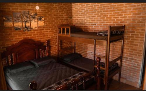 sypialnia z 2 łóżkami piętrowymi i ceglaną ścianą w obiekcie Nosso Recanto Gaúcho Paraíso no interior Guaratinguetá Aparecida w mieście Guaratinguetá