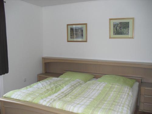 1 cama con sábanas verdes y 2 cuadros en la pared en Haus Weiche, en Flensburg