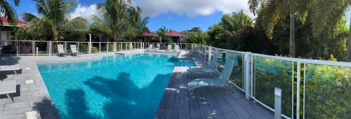 a large swimming pool next to a white fence at Hôtel & Villa Le Cocotel in Saint-François
