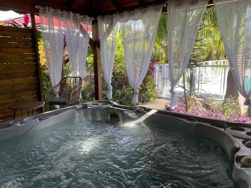 a jacuzzi tub in a backyard with curtains at Hôtel & Villa Le Cocotel in Saint-François
