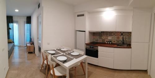 kuchnia z białymi szafkami i stołem z krzesłami w obiekcie Piso pl 2A, 20 min Plaza Cataluña w mieście Sant Adria de Besos