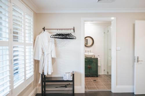 a bathroom with white walls and a closet with a mirror at Birches Mudgee in Mudgee
