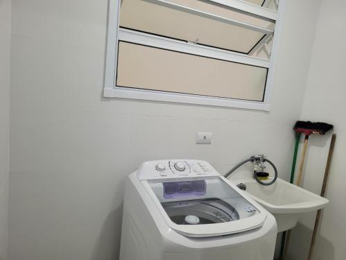 a washing machine in a bathroom next to a sink at APARTAMENTO PRÓXIMO A PRAIA PISCINA E AREA GOURMET in Ubatuba