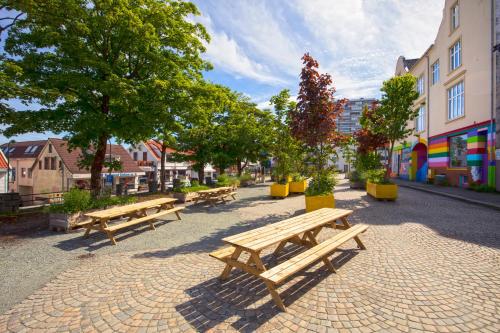 a row of wooden benches sitting on a street at Central Studio Apartment in Stavanger in Stavanger