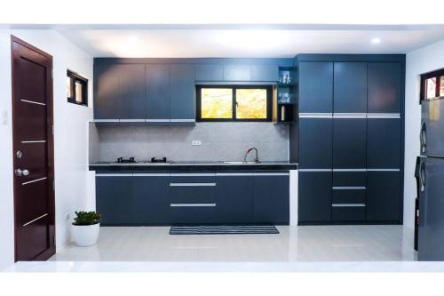 eine Küche mit dunkelblauen Schränken und einem Waschbecken in der Unterkunft At Home With Kajea 