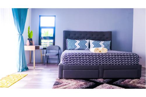 Schlafzimmer mit einem Bett mit blauen Wänden und einem Tisch in der Unterkunft At Home With Kajea 
