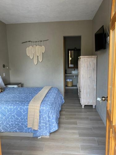 a bedroom with a blue bed and a bathroom at Hotel Casa Caro in Bernal