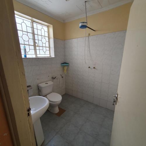 uma casa de banho com um WC, um lavatório e uma janela em Château Lake-ish em Nakuru