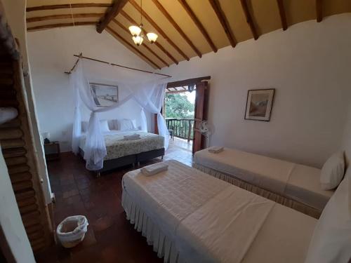 a bedroom with two beds and a balcony at Posada Sueños de Antonio in Barichara