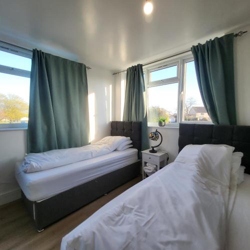2 łóżka w sypialni z zielonymi zasłonami w obiekcie Fully Furnished 2 bedroom apartment with 4 single beds w Bristolu