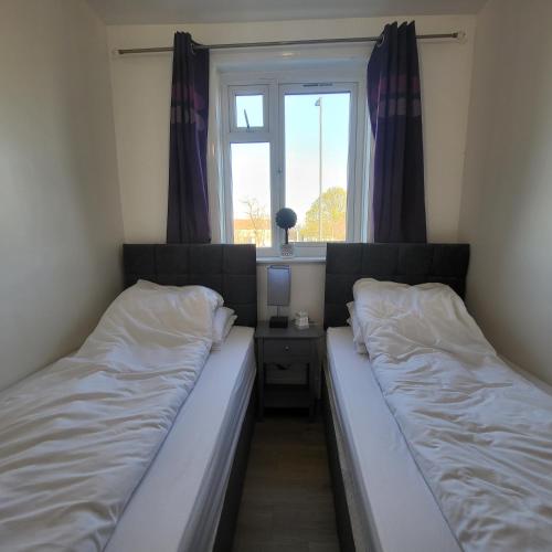 2 łóżka w małym pokoju z oknem w obiekcie Fully Furnished 2 bedroom apartment with 4 single beds w Bristolu