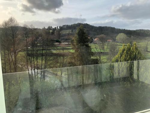a view of a field from a glass window at Restaurante Residencial Pizzaria S. Estevão in Aguiar da Beira