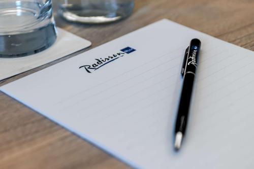 a pen sitting on top of a paper on a table at Radisson Blu Hotel Riyadh Convention and Exhibition Center in Riyadh