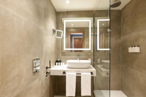 a bathroom with a sink and a glass shower at Radisson Hotel Ferrara in Ferrara