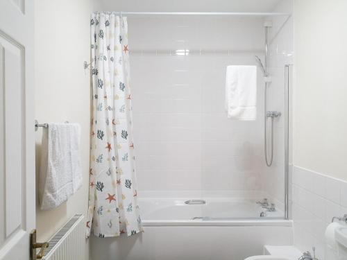 uma casa de banho branca com uma banheira e um chuveiro em Apartment 15 Harvest Moon em Newquay