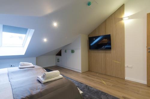 two beds in a room with a tv on the wall at Mayisa Apartments in Sarajevo