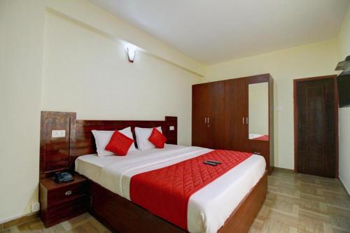 ein Schlafzimmer mit einem großen Bett mit roten Kissen in der Unterkunft Pinehill Suits in Udagamandalam