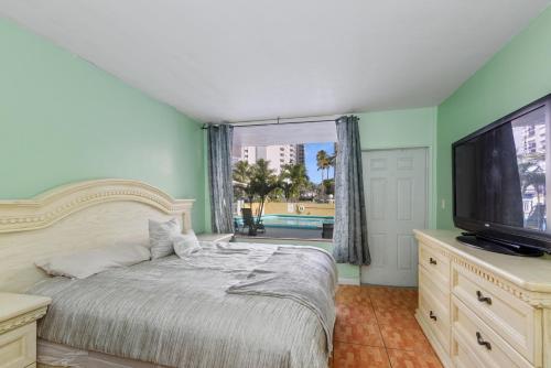 1 dormitorio con 1 cama, TV y ventana en Sky Islands Beach, en Fort Lauderdale