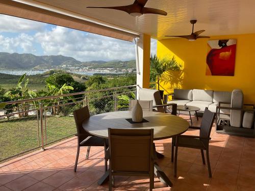a patio with a table and chairs and a balcony at BAS DE VILLA PISCINE PETIT VERSAILLES SAINTE ANNE in Sainte-Anne