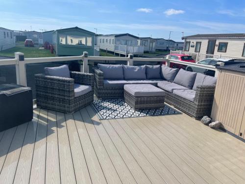 a patio with a couch and chairs on a deck at Trecco bay caravan hire 4 bedrooms sleeps 10 in Porthcawl