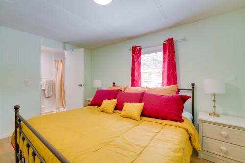 a bedroom with a bed with red and yellow pillows at Fire Pit and Boat Dock Peaceful Dunnellon Cabin! in Dunnellon