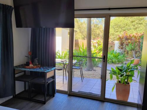 a room with a sliding glass door with a table at Beachside One Bedroom Flat Retreat in Maroochydore