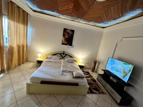 a bedroom with a bed and a flat screen tv at Prodiges Hôtel in Yaoundé