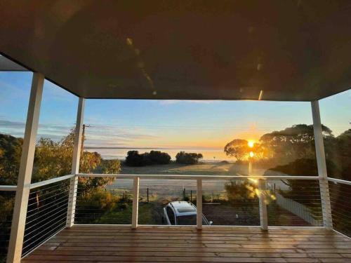 a view of the sunset from the porch of a house at Beachfront 4 Bedroom Home in Nepean Bay in Nepean Bay