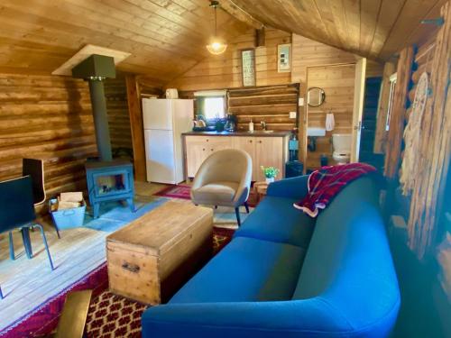 a living room with a blue couch and a kitchen at Chute Lake Lodge in Naramata